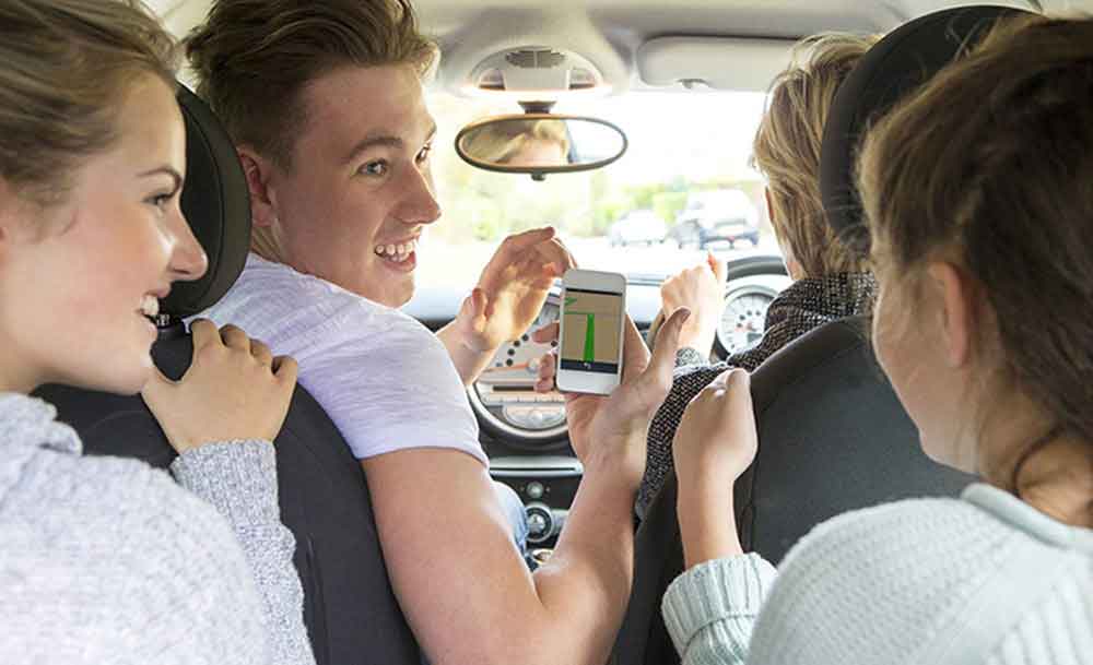 teenager in car showing others his mobile phone