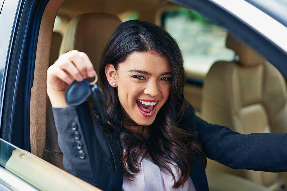 happy woman in car with keys