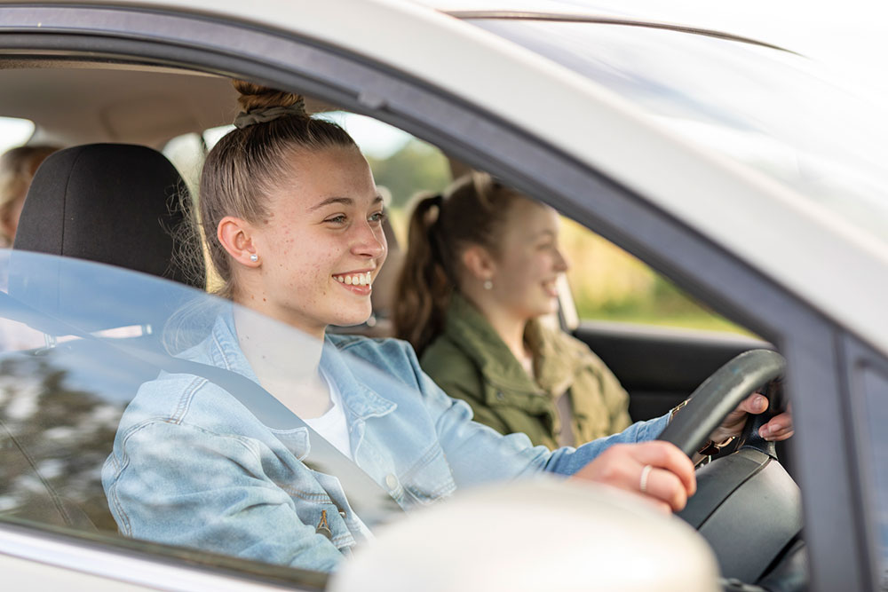 Young driver behind the wheel with friend in passenger seat.