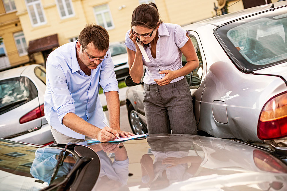 Two people exchange details after a road accident.