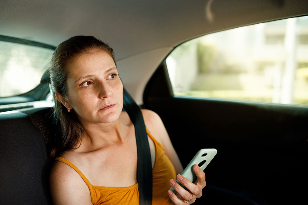 Nervous-looking woman passenger in car.
