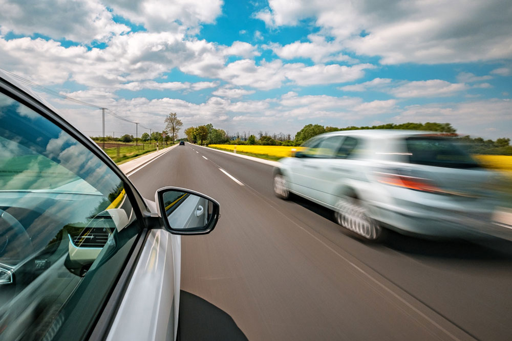 Car being overtaken on a highway.