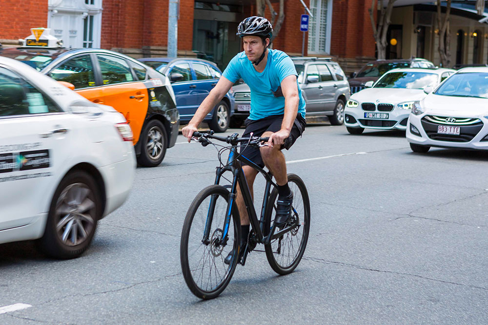 Man riding bike through city traffic.