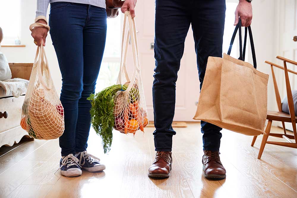 couple holding reusable grocery bags