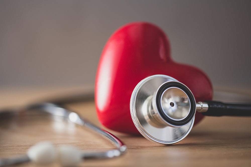 Stethoscope in front of a plastic heart.