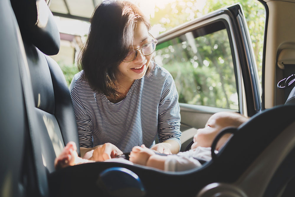 Mother putting baby in car seat.