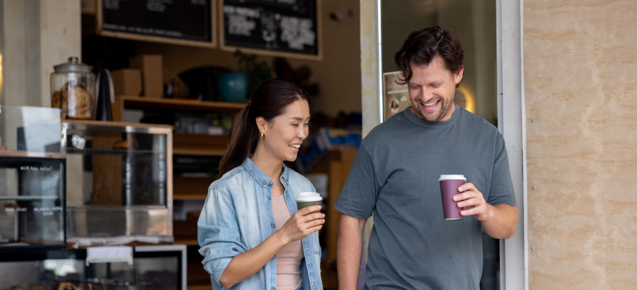 Man and woman leaving a cafe after buying takeaway coffee