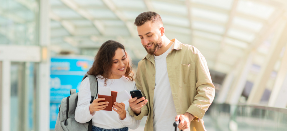 Couple with phone and suitcase inside airport