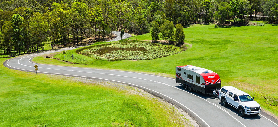 Car towing caravan driving along road at Mount Cotton