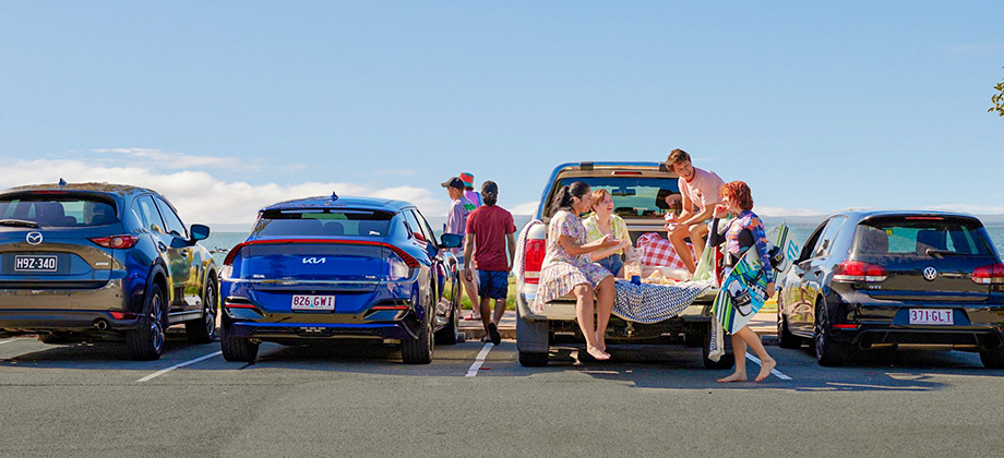 people at the beach in front of parked car