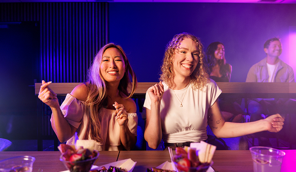 Two people enjoying food and drinks at a VIP lounge during a Brisbane Entertainment Centre experience.