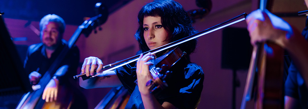 QSO-John Williams-Orchestra-girl-playing-instrument-1000x354px