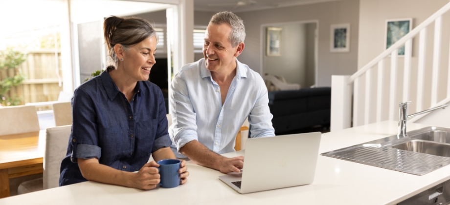 Couple at kitchen bench looking at laptop