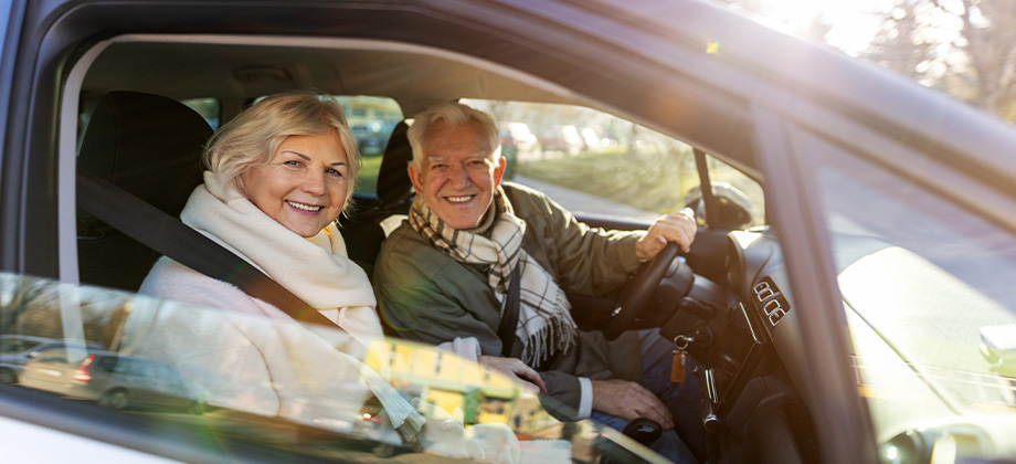 senior couple parked car smiling