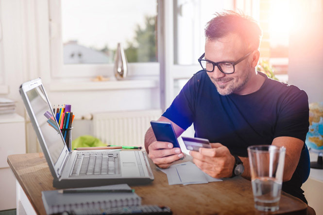 m38-smiling-man-checking-mobile-credit-card-resized