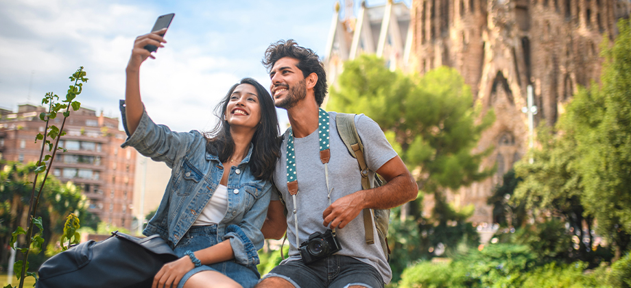 Male and female travelers sitting in park near Sagrada Familia in Barcelona
