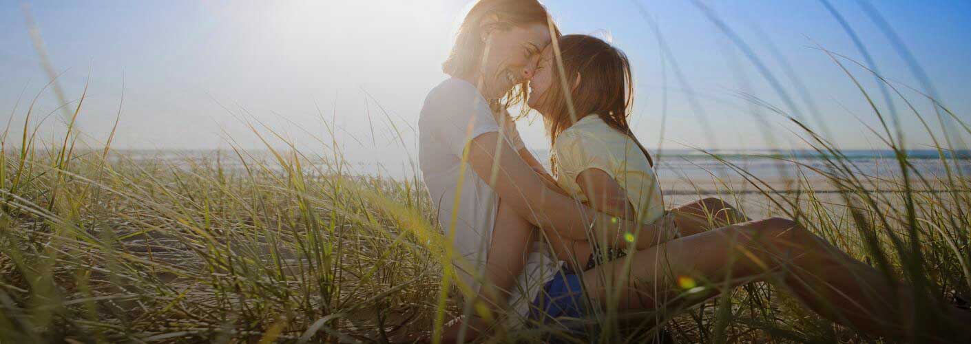 mother-and-daughter-embracing-near-the-beach-1410x500