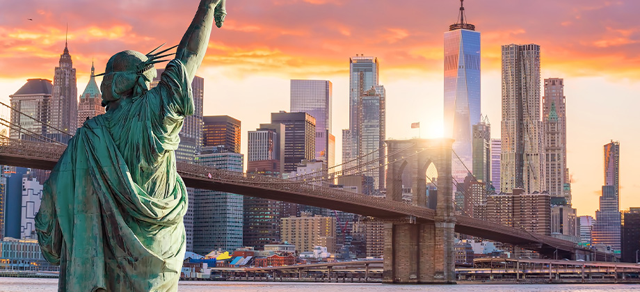 statue liberty and new york city skyline at sunset
