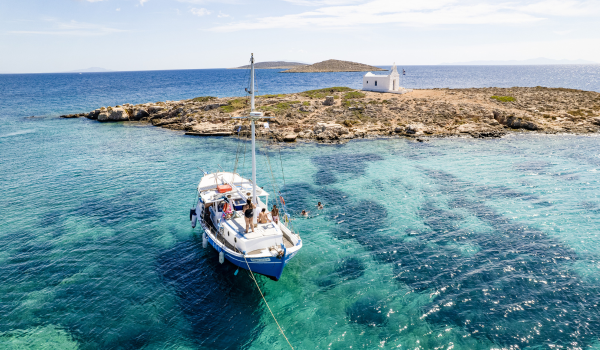 Sailboat anchored in clear turquoise waters off a rocky Croatian island