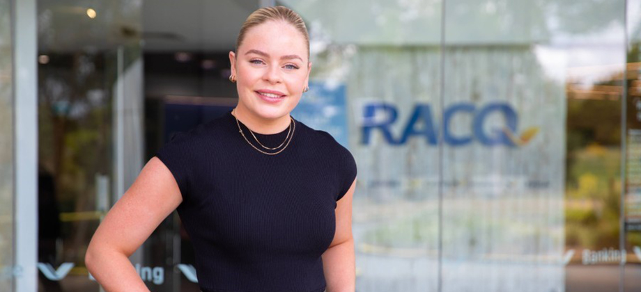 racq staff employee in front of RACQ logo