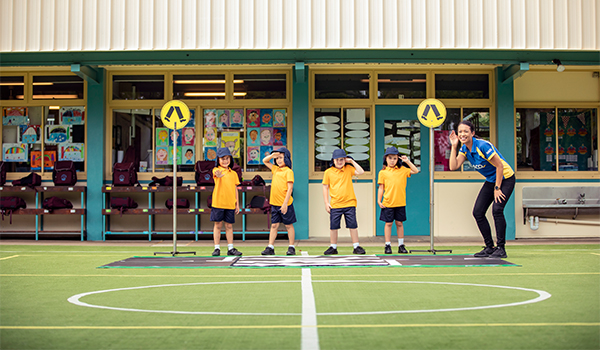 School students outside in yellow shirts next to pedestrian and RACQ rep 600x350