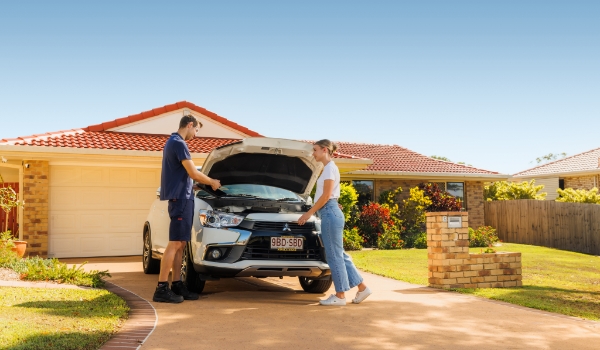 Man showing young woman car maintenance