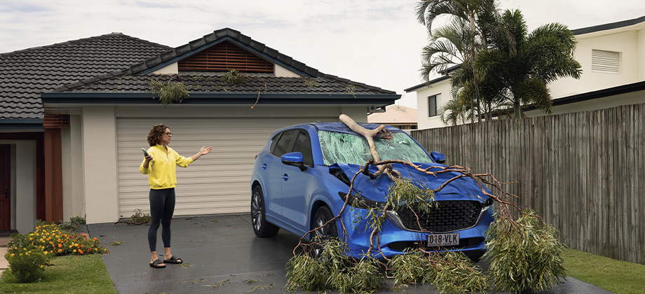 woman upset at weather damaged car after storm